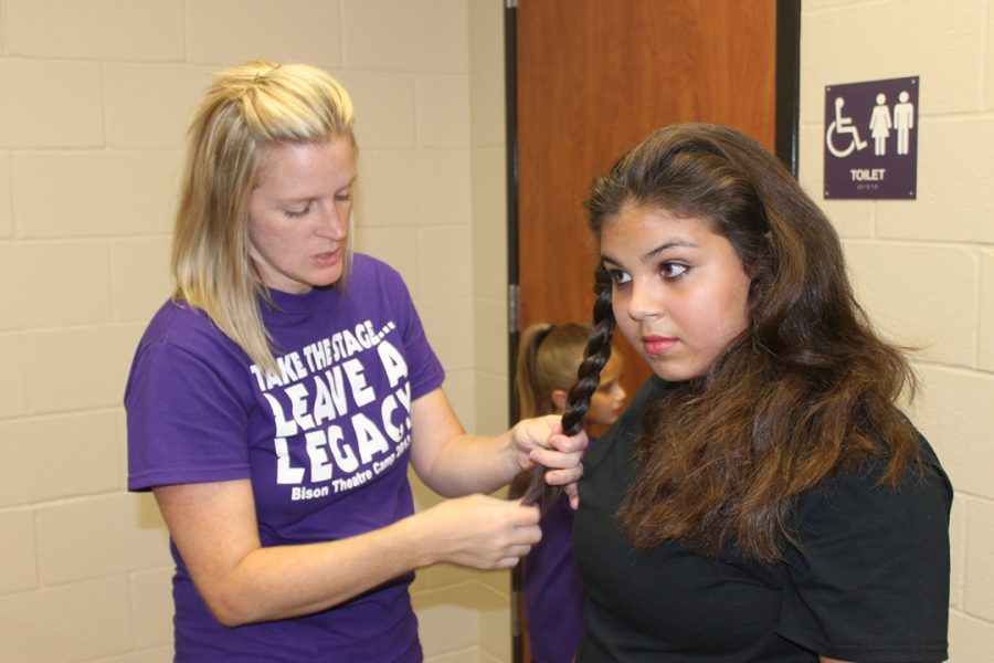 Theater director Jill Henson helps junior high student Mackenzie Morales fix her hair before the theater camp production of The Wizard of Oz.