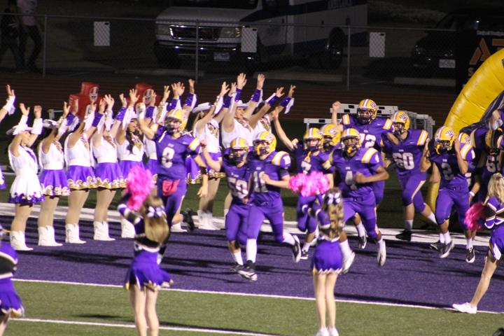 The cheerleaders sport pink poms while the football players fun through the victory line at Friday nights Pink Out game.