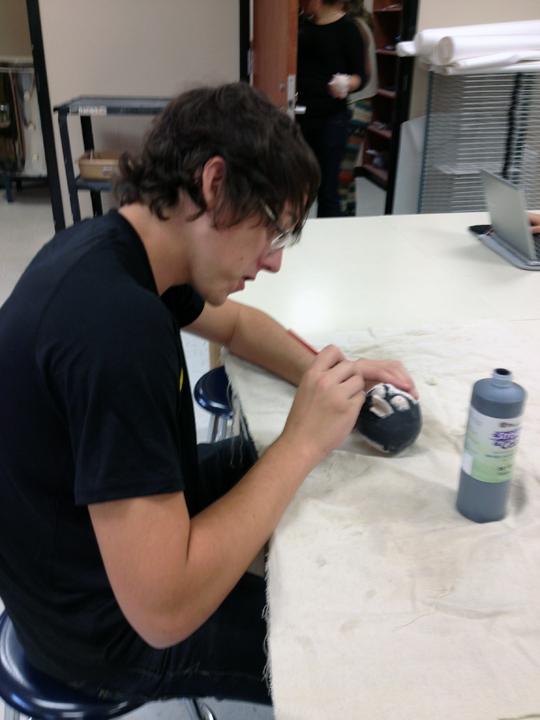 Senior Ryan Slatter works on adding color details to his Angry Bird using ceramic glaze. The class created owl sculptures after their Angry Birds. 
