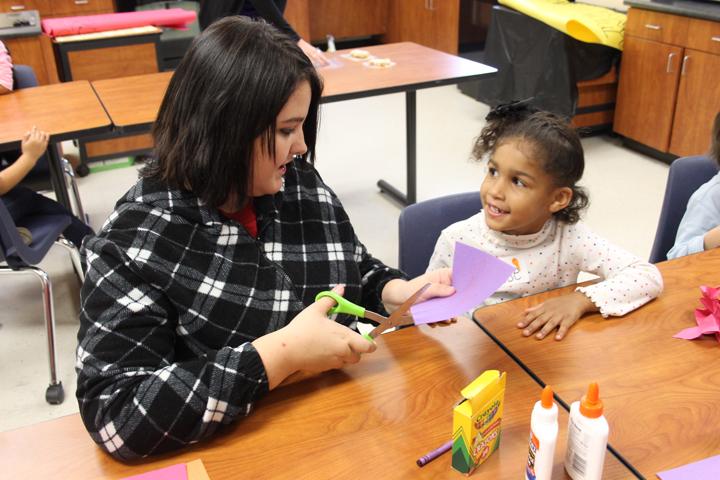Sophomore Kel-C Lesley works with a kindergartener on her part of the poster the students made for their teachers. 