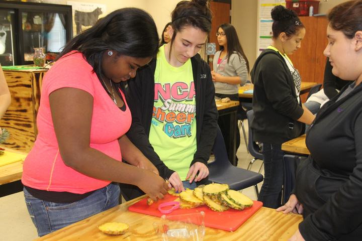 Floral arrangement students Adrian Randle and Raina Cain work on cutting pineapple for edible arrangements. The teachers enjoyed the arrangements as Valentines Day treats.