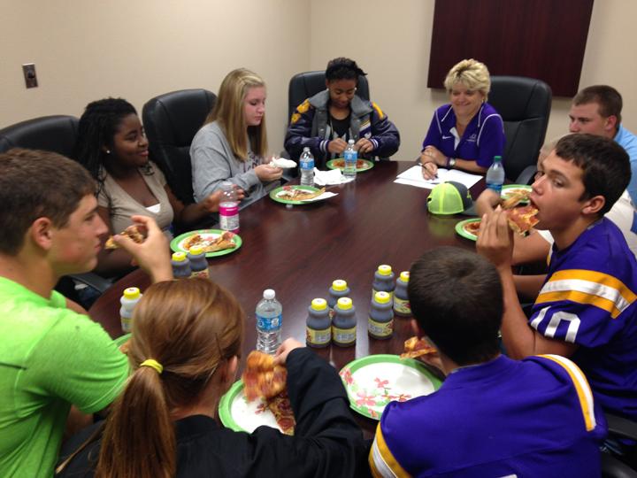 Principal Tracy Gleghorn and members of the Student Advisory Committee share a pizza lunch while planning bonfire