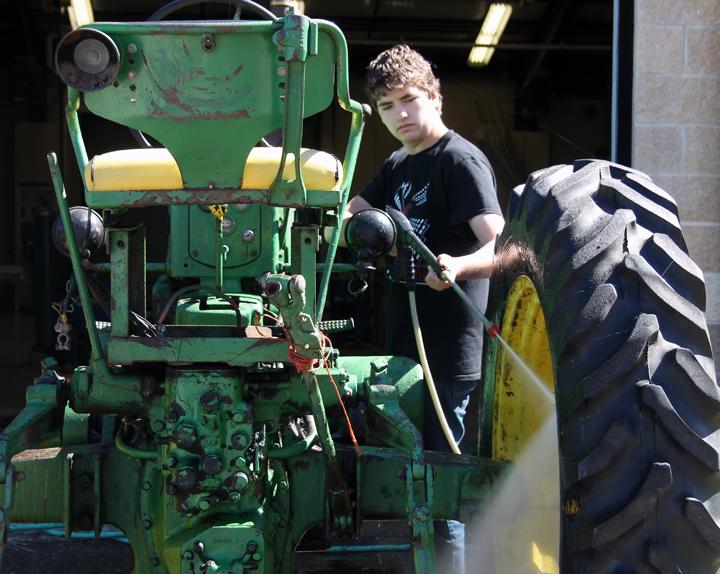 Sophomore+Steven+Millar+works+on+pressure+washing+the+tractor+that+his+ag+class+is+restoring.