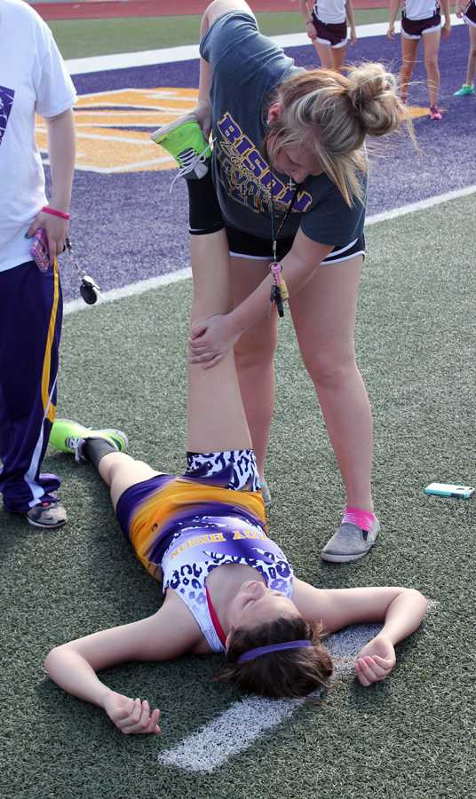 Junior Makayla Troyer helps the runners stretch before the meet. 