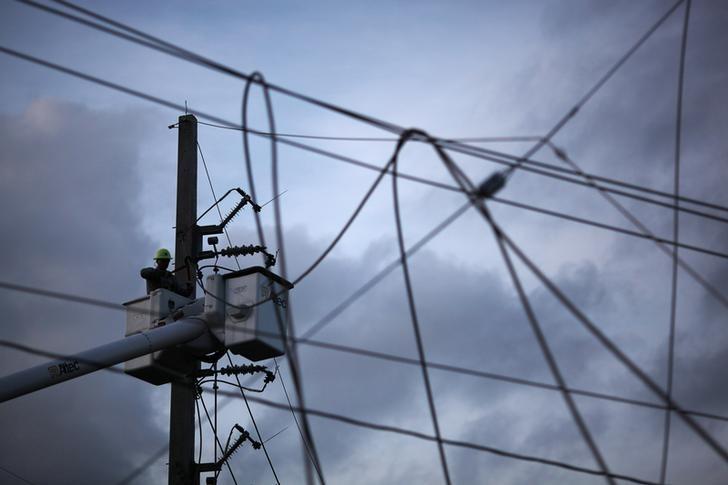 A worker of Puerto Ricos Electric Power Authority (PREPA) repairs part of the electrical grid after Hurricane Maria hit the area in September, in Manati, Puerto Rico October 30, 2017. REUTERS/Alvin Baez
