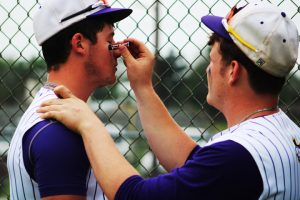 Sophomore Zayne Johnson helps senior teammate Brett Hoffman get ready for their last game of the season. The seniors, including Brett, and their parents, were honored before the game. 