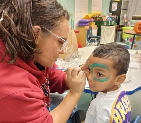 Junior Alexis ODaniel focuses on keeping her hand steady while she paints faces for the kindergarten class.