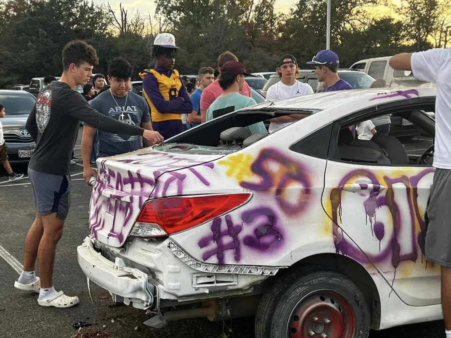 Football players spray paint an old car before they tear it apart to symbolize what they hope to do to Boling tomorrow night.