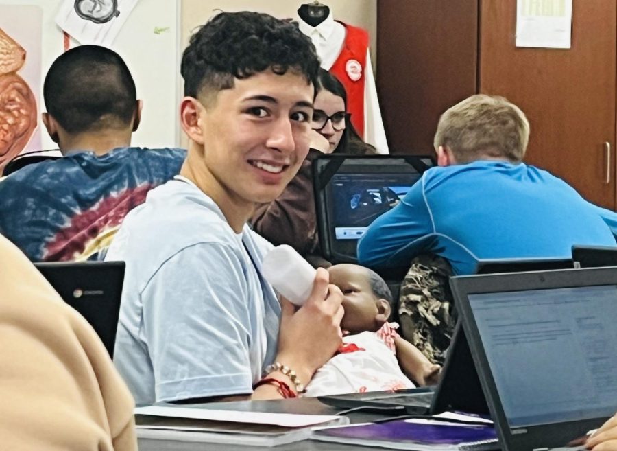 Junior Luis Ortiz takes care of his infant during class, stopping his work to offer a bottle and keep the baby from disturbing the other students.