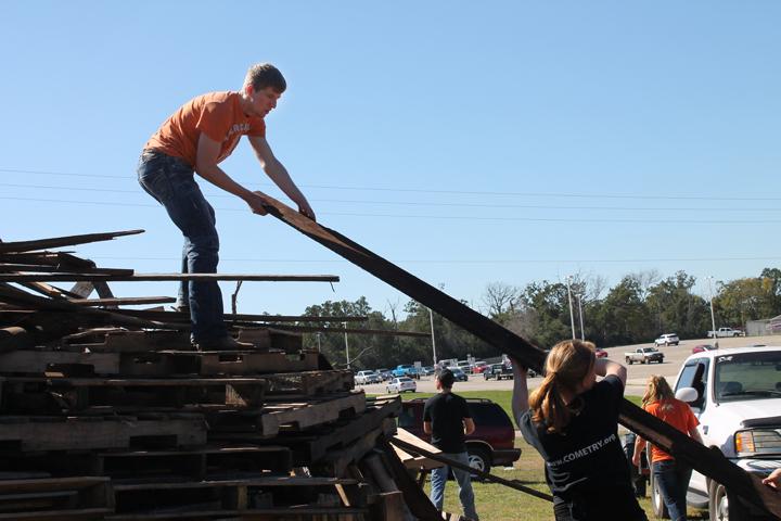 Senior Jacob Davis helps to life wood high up onto the stack.