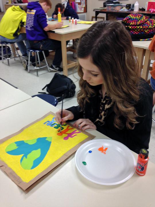 Sophomore Ally Gaskins works on her bag for art class. The students used acrylic paints on brown paper bags to complete the projects.