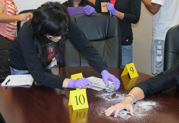 Senior Marisol Lopez collects evidence from the powdery substance spilled around victim Janet Slaughter. 