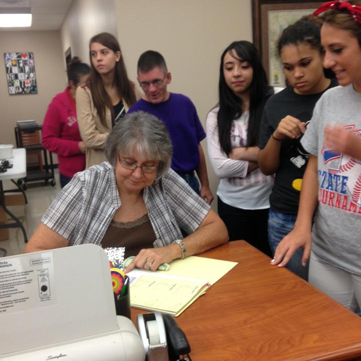 Secretary Beverly Cummings writes receipts for Chromebook insurance while students wait their turn. 