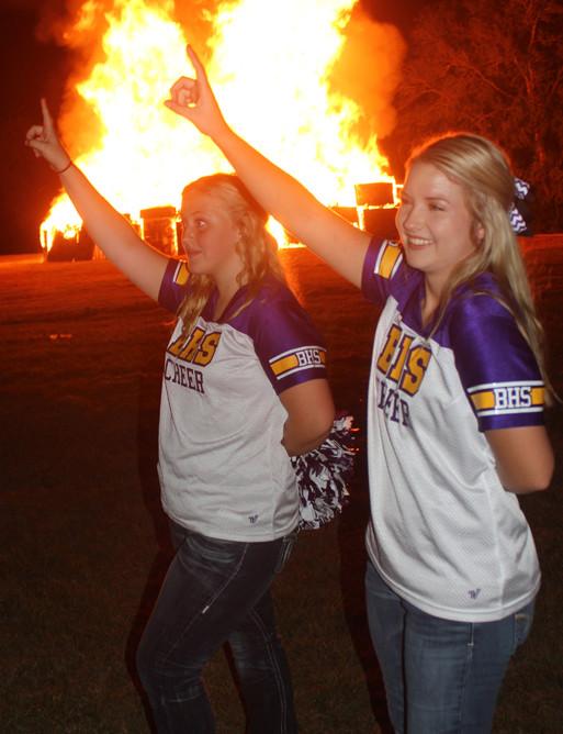 Senior Haley Martin and junior Jacie Jones join in the singing of the school song during bonfire.