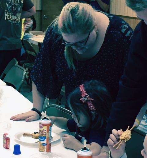 Junior Katelyn Cannon helps a preschooler create a Halloween snack before a trip to the Pumpkin Patch.