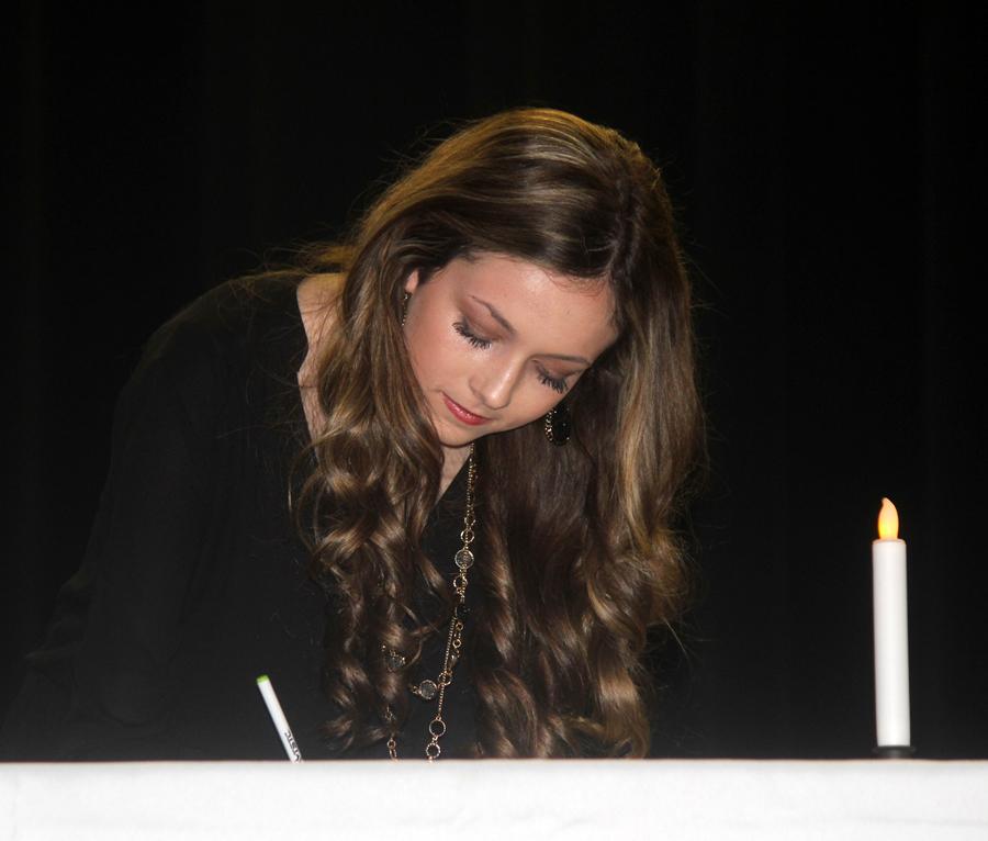 Sophomore Ally Gaskins signs the membership book during the NHS induction.