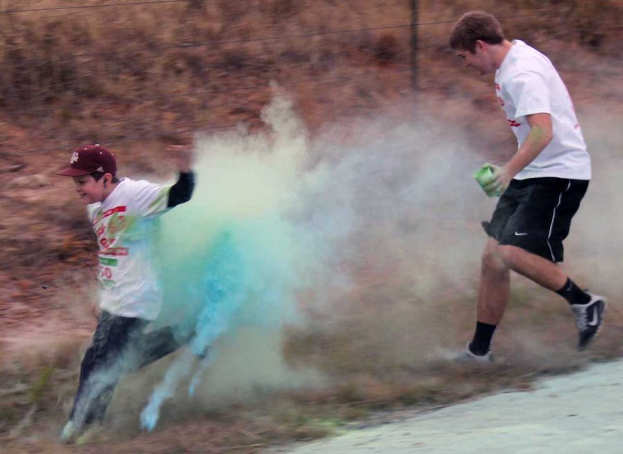 Junior Logan Freeman chases a young runner off the road to hit him with color powder during the 4-H Jingle Bell Color Run last weekend. 