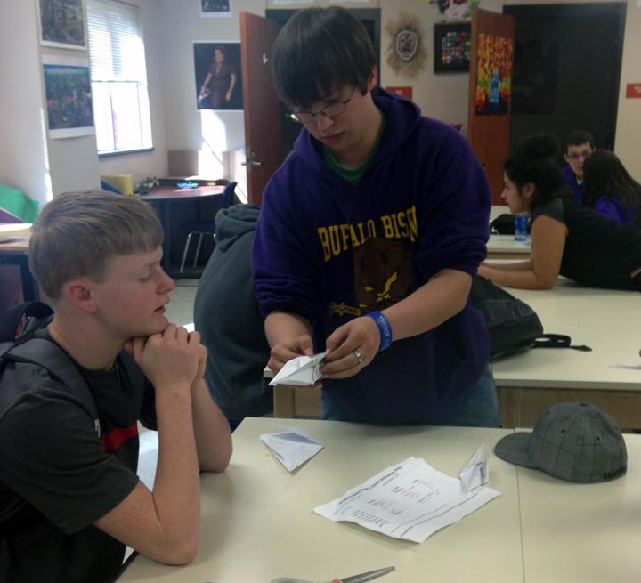 Junior Austin Melton shows sophomore Dillon Beshears how to make a paper swan in art class.