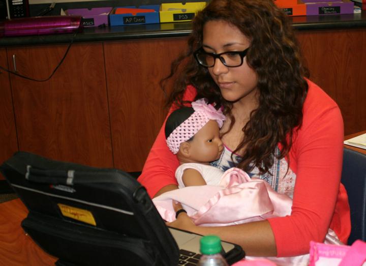 Senior Miryam Zapata takes care of a simulator baby while working on an assignment.