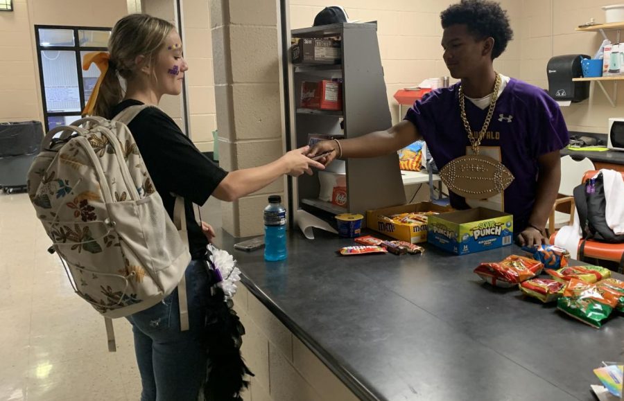 Sophomore  Aiden  Savage  waits  on  customer Caidence King at the concession stand after school. The after-school  hours have been a big hit with students on their way to the  bus.