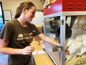 Sophomore Emma Cocking fills popcorn bags while working the concession stand during a JV football game. 
