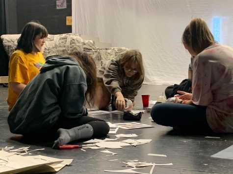 Junior Lindsey Hardin reaches for the tape while she and other cast and tech members put together masks for the musical.