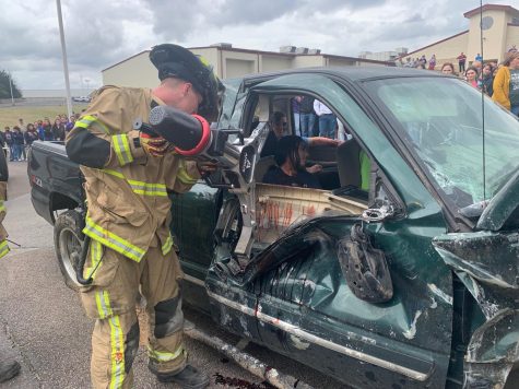 A Buffalo VFD member cuts away part of a wrecked car during the Shattered Dreams program. High school students watched from the parking lot.