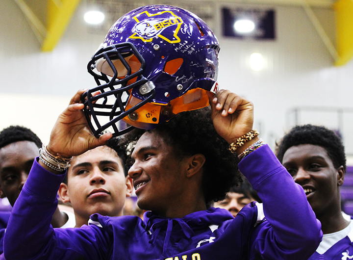 Senior Aiden Savage holds up the football helmet autographed by the varsity team. The helmet, as well as multiple district passes, parking spaces and baked goods raised nearly $20,000 for student groups.