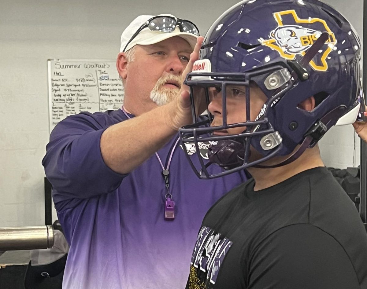 Coach Jesse House lends a hand putting decals on helmets at Decals with Dad. This is the second year for the team to host the event.
