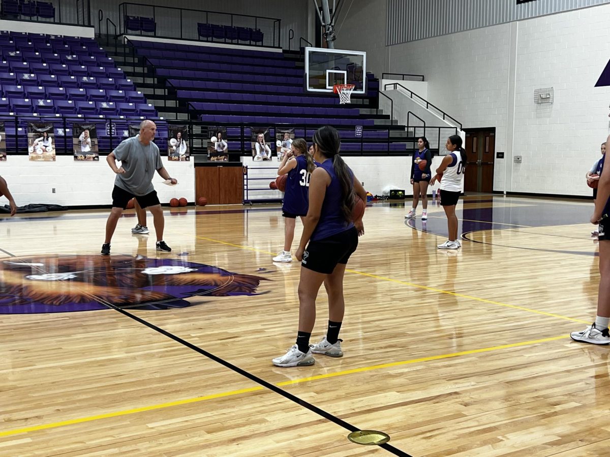 Coach Chuck Winkelman offers tips on dribbling during an early-morning practice. The Ladies started daily basketball practices as soon as volleyball ended.