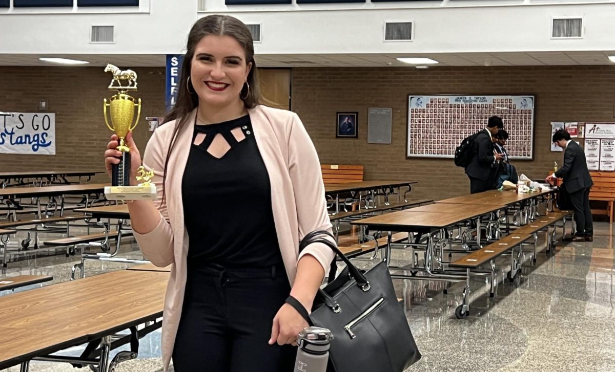 Senior+Nicollette+Arabie+shows+off+the+trophy+she+earned+at+the+Katy-Taylor+tournament.+She+placed+in+both+Extemp+and+Impromptu.