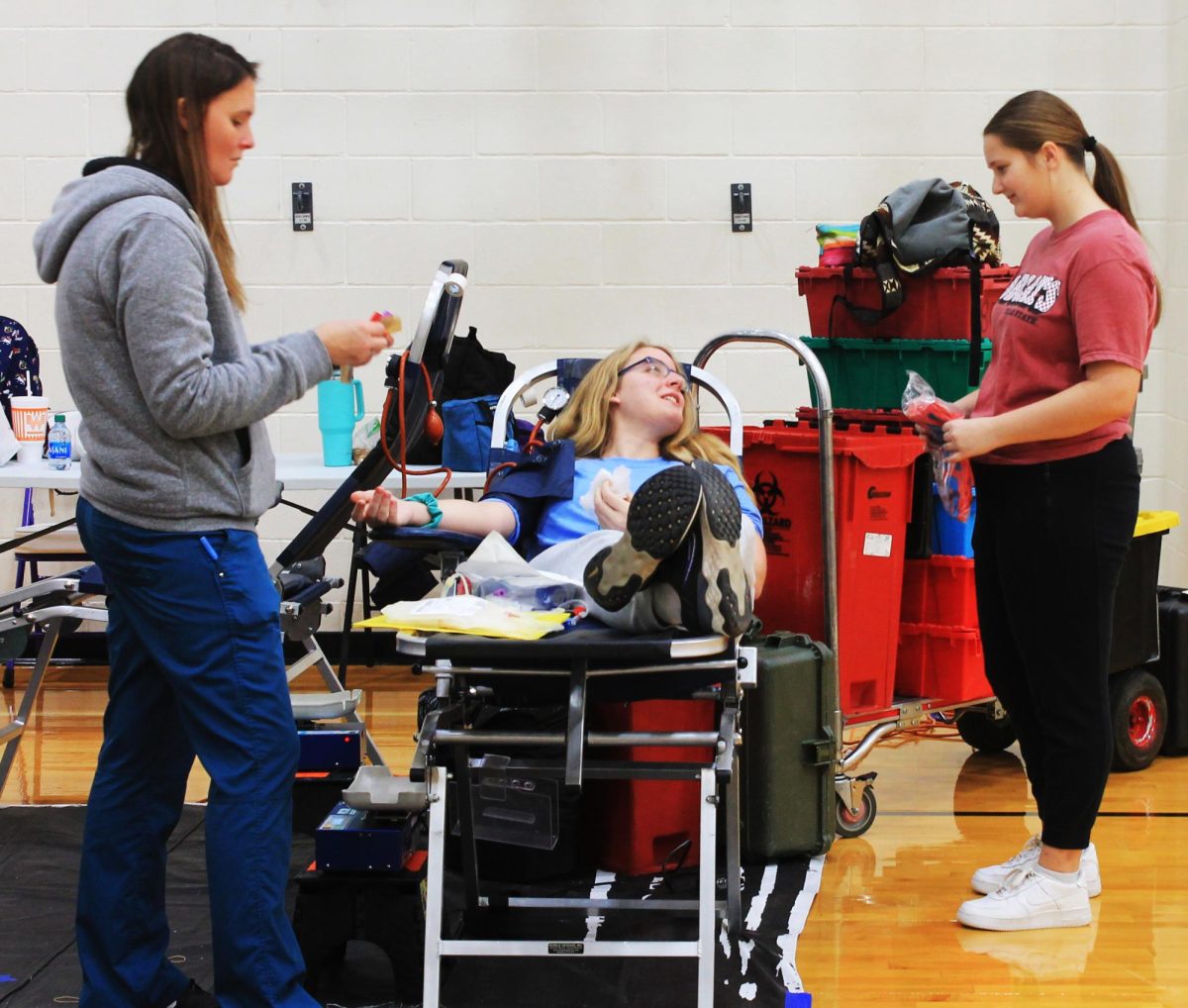 Junior Tristan Cole visits with NHS member  Bradyn Lack while she donates blood. Lack is one of the members who volunteered to help run the event. 