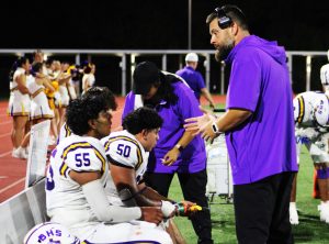 Coach Cameron Wendel talks to players on the sidelines between plays. The weather was hot and muggy and both teams struggled with cramps.